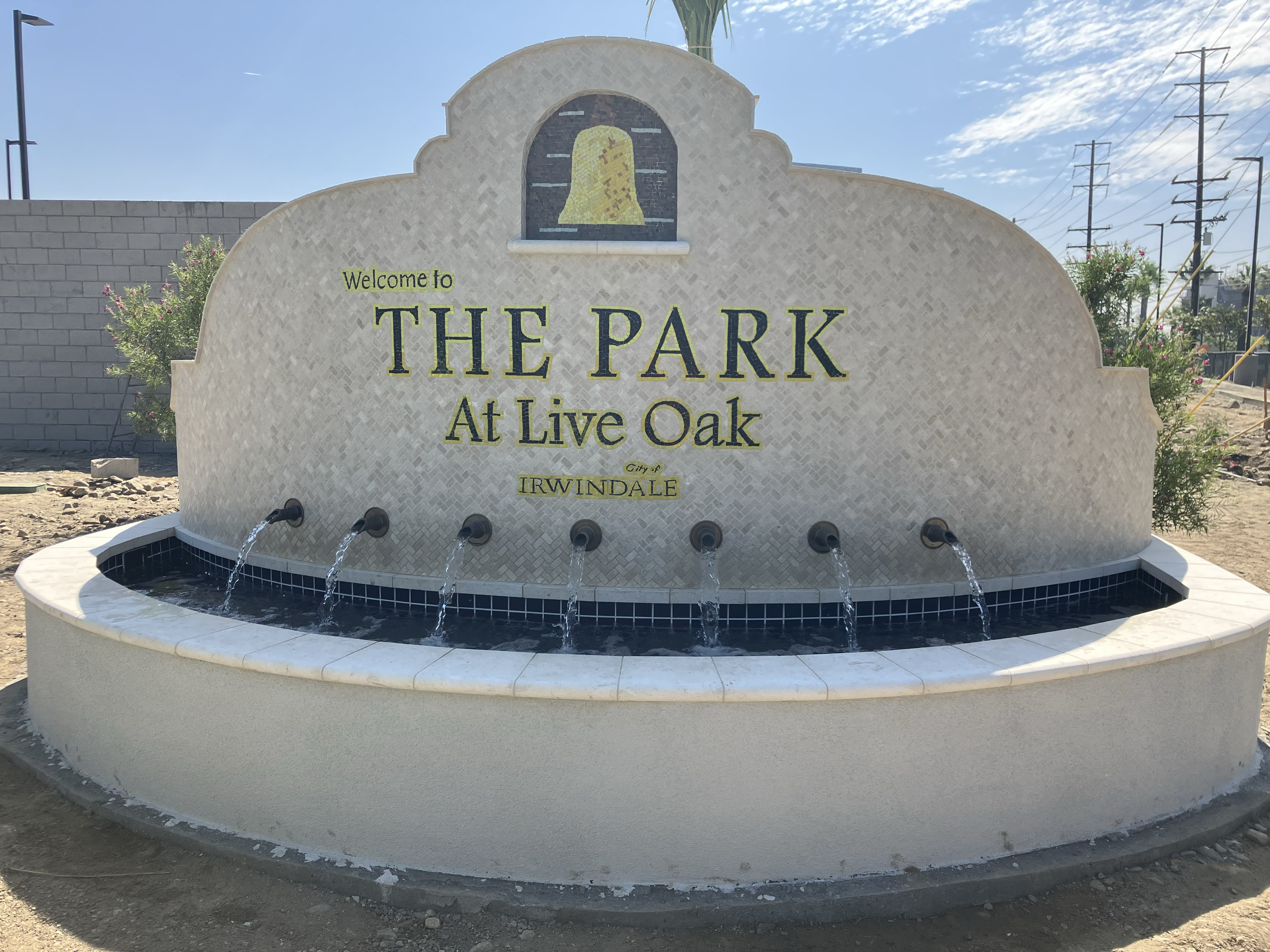 The Park At Live Oak sign in Irwindale with a bell mosaic and fountain.